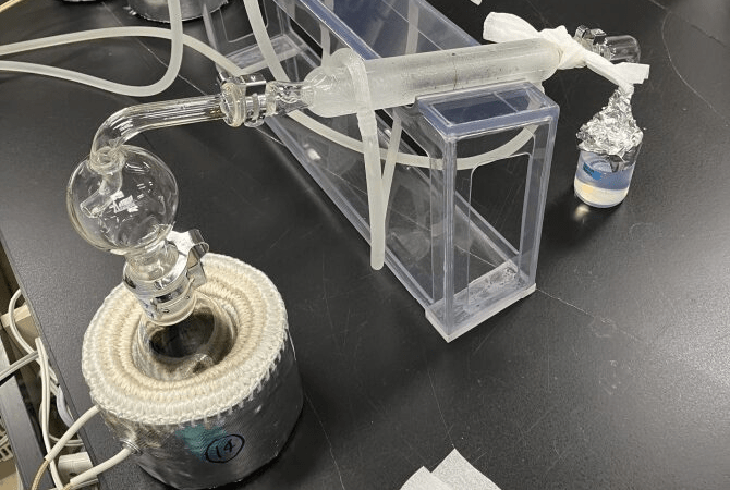前処理（リービッヒ冷却管を用いた蒸留による分離）<br>※左の容器に試料を入れて、加熱するとトリチウムを含む水は水蒸気となる。中央の冷却管にて水蒸気を冷却し右の容器に水として回収する。妨害物質は左の容器に残るため、トリチウムを含む水を分離できる。
